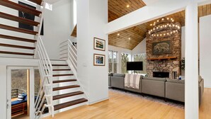 A spacious living area with a wooden staircase, a stone fireplace, and a large sofa. - Amazing Views / Hot Tub / 15 mins to Wineries / 3200 sq ft (Wintergreen Resort)