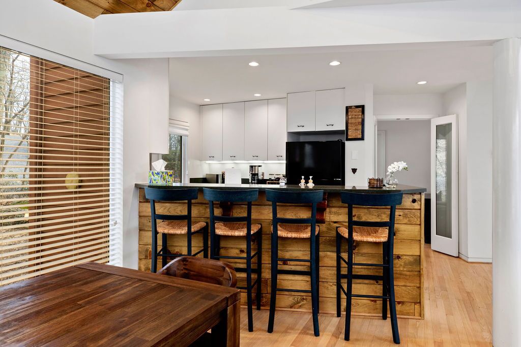 A modern kitchen with white cabinets, a black refrigerator, and a wooden island with bar stools.