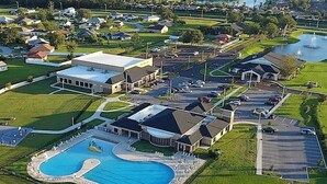 An aerial view of a residential area with a large swimming pool, multiple houses, and a golf course. - Uniquely Chic home near Disney! (Kissimmee)