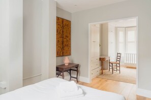 Une chambre à coucher comprenant un lit, un bureau, une chaise, une commode et un grand miroir.