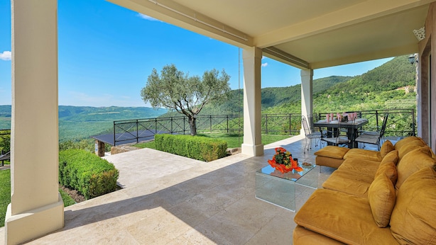 A covered outdoor seating area with a view of a mountainous landscape, a dining table with chairs, and a sofa. - Villa Over the Hilltop by Interhome (Motovun)
