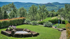A garden with a stone fire pit, a pathway, and a view of a town in the distance. - Villa Over the Hilltop by Interhome (Motovun)