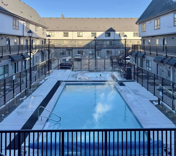A swimming pool surrounded by apartment buildings with balconies and railings.