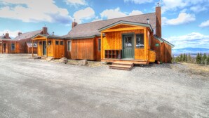 A row of wooden cabins with a gravel driveway and a clear sky.