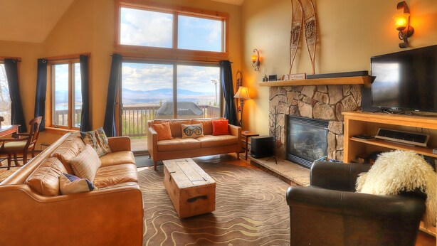 A spacious living room with a large window, a fireplace, and a television.