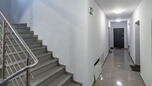 A modern hotel hallway with a staircase, a door at the end, and a ceiling light. - Janasa Comfort Studio (Katowice)