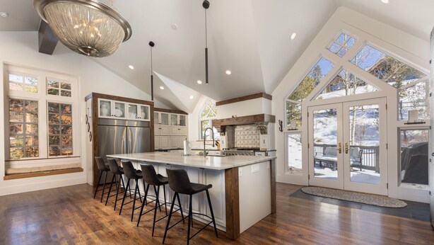 Una cocina amplia con una isla grande, piso de madera y una lámpara moderna.