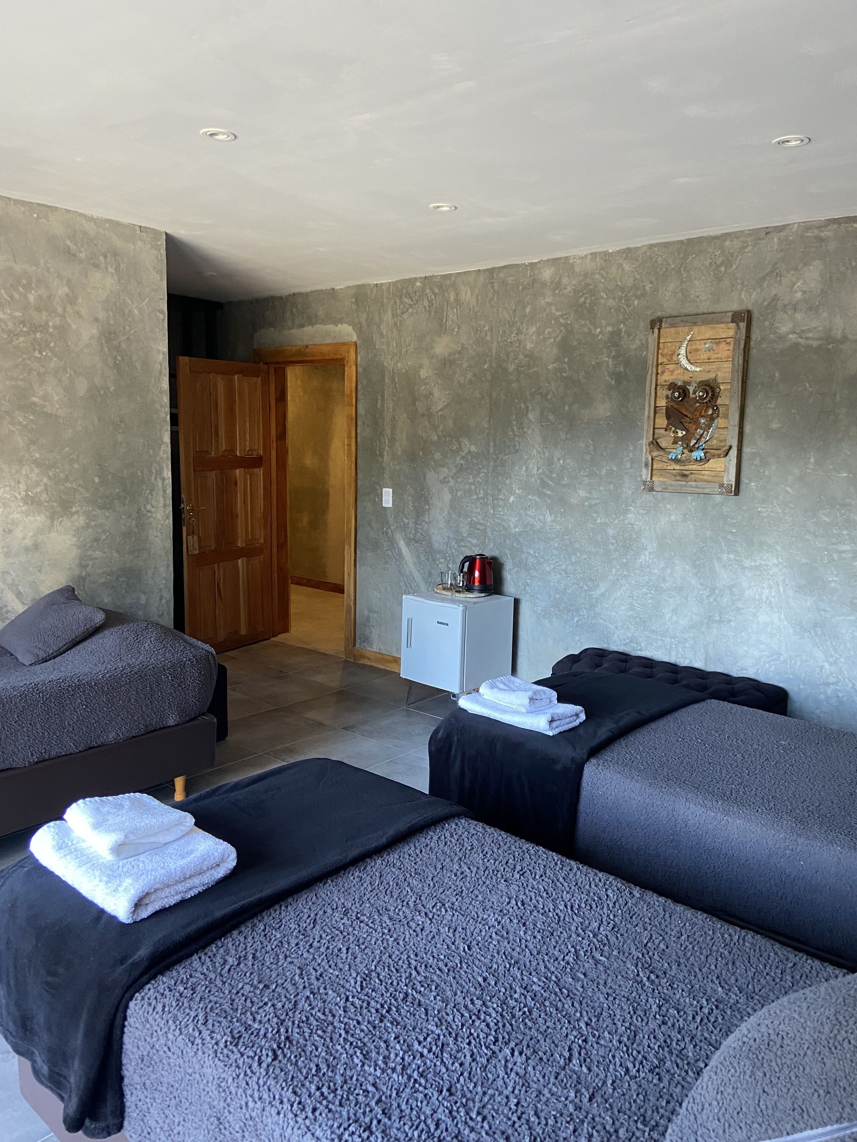 A room with two beds, a small cabinet, and a painting on the wall.