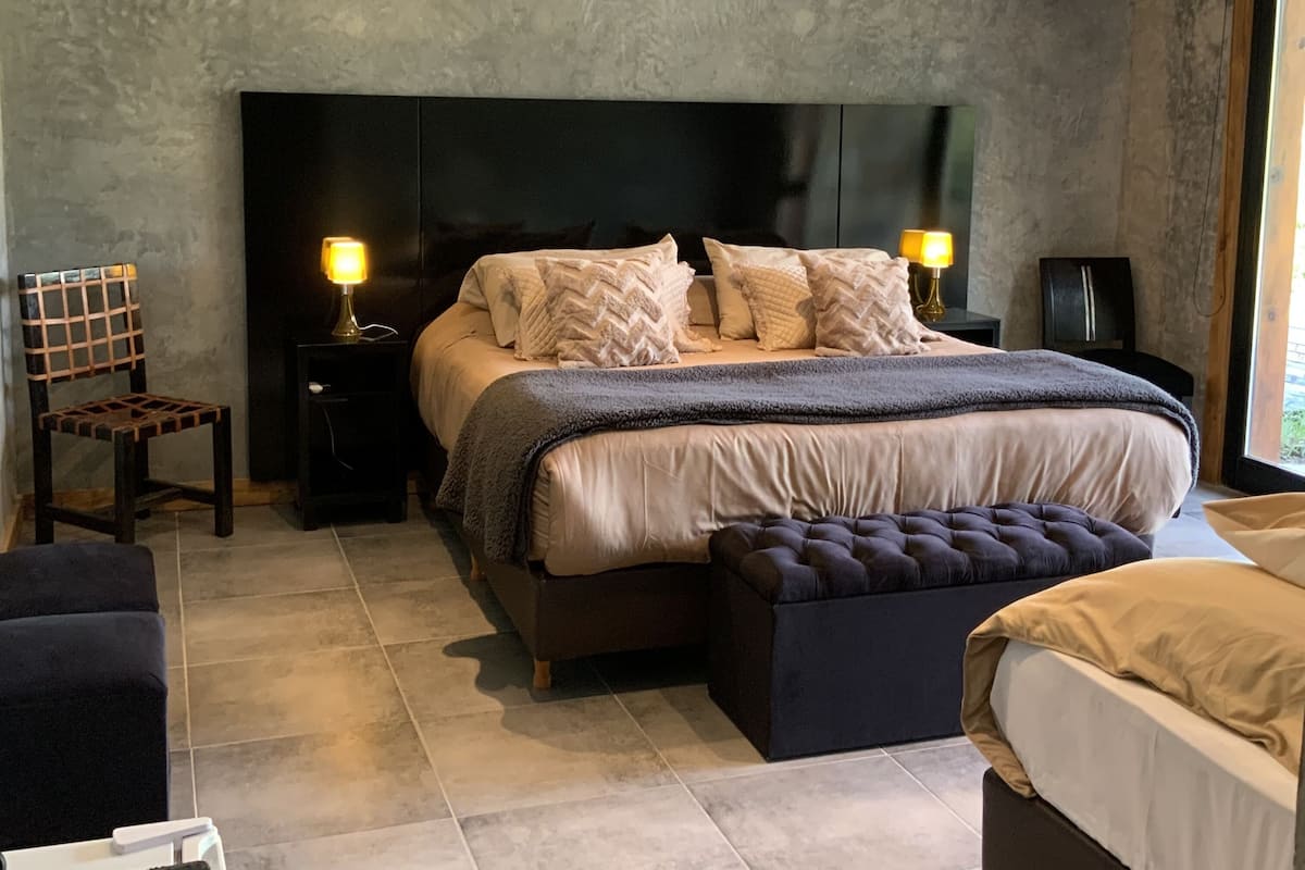 A bedroom with a large bed, two bedside tables, a chair, and a bench.