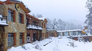 Ein schneebedecktes Gebäude mit einer steinernen Fassade und einem Balkon.