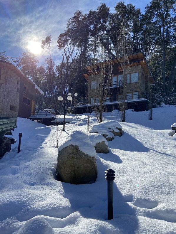 Un paisaje nevado con un edificio de piedra, una estructura de madera y un cielo despejado.