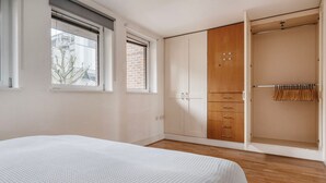 Une chambre à coucher comprenant un lit, une armoire et un placard avec une tringle pour suspendre les vêtements.