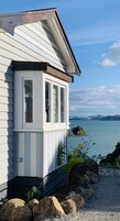 Una casa costera con fachada blanca, un ventanal y vista al mar.