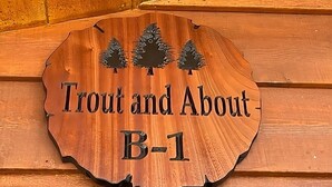 A wooden sign with the text "Trout and About B-1" and three pine tree silhouettes. - Cozy cabin in delightful Kemmerer with AC, WiFi (Kemmerer)