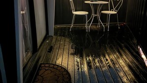 An outdoor patio with two white metal chairs and a small table, surrounded by string lights. - Stylish tiny home in Melton west (Melton West)