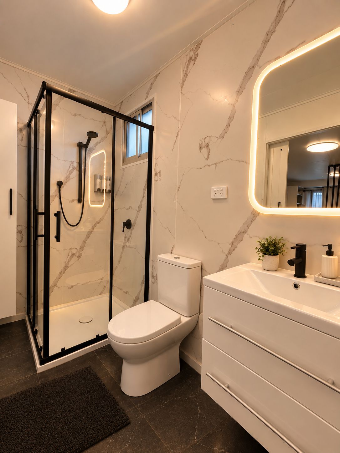 Un baño moderno con ducha envuelta en vidrio, inodoro y tocador con espejo.