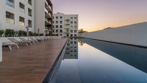 A modern hotel with a rooftop pool, lounge chairs, and a reflection pool. - Elegant Penthouse with Private Terrace, BBQ & Jacuzzi (Cabo San Lucas)