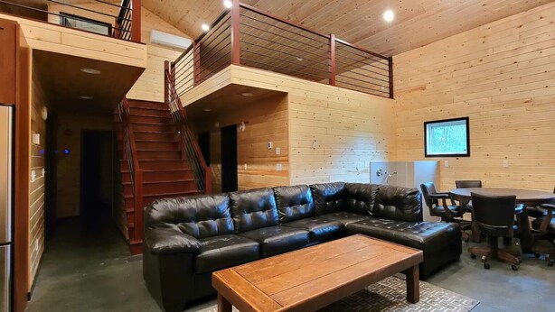 A wooden interior with a sectional sofa, a coffee table, and a dining area with chairs.