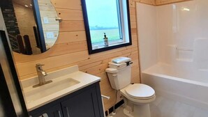 A bathroom with a wooden interior, a white sink, a toilet, and a bathtub.