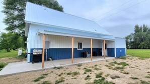 A single-story building with a blue and white exterior, a covered porch, and a barbecue grill outside.