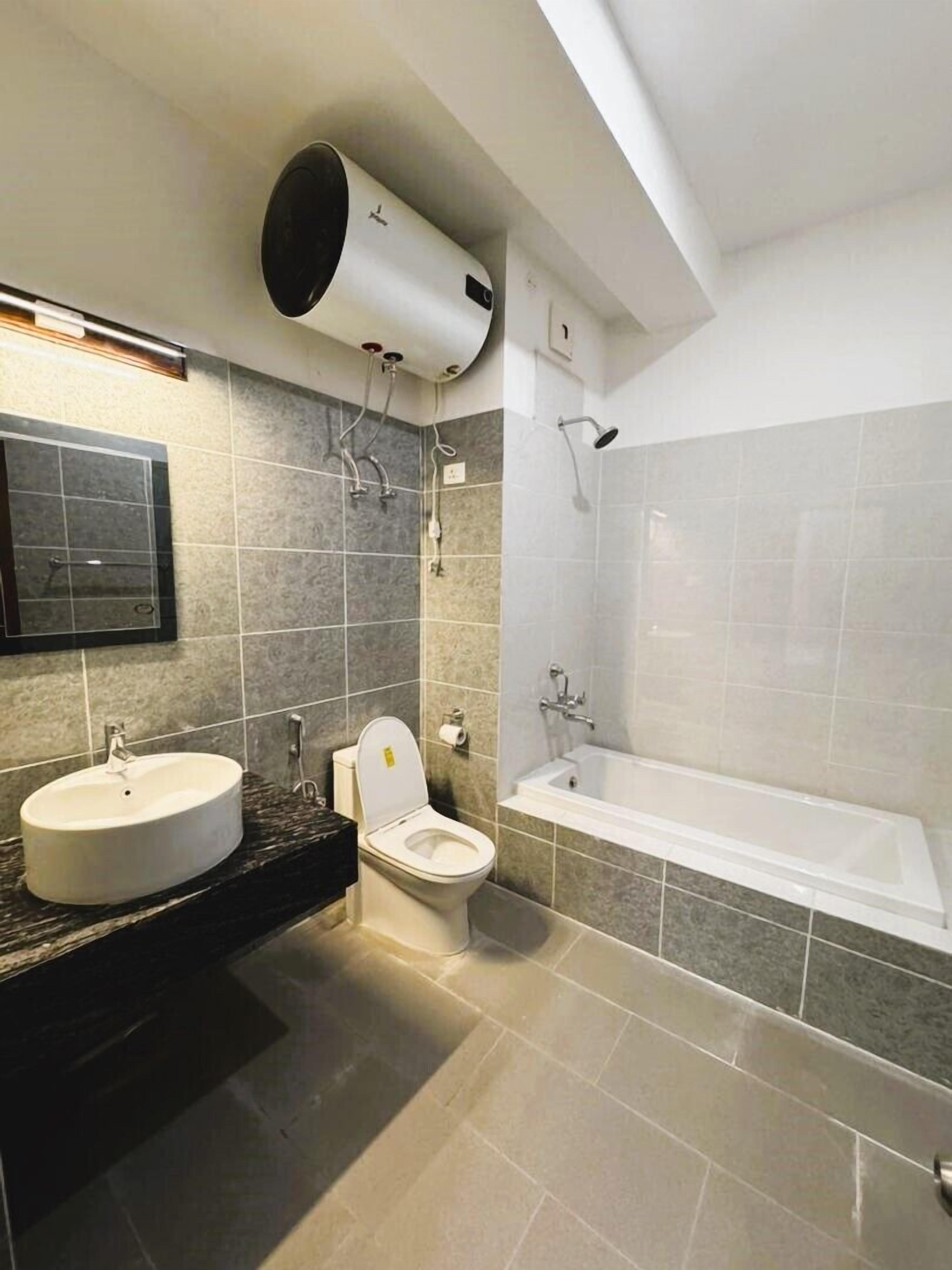 A modern bathroom with a sink, toilet, and bathtub.