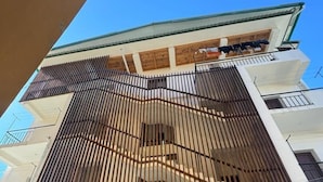 Un immeuble à plusieurs étages doté d’un design moderne, avec une série de balcons et une façade en briques.