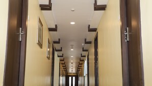 A long, narrow hallway with wooden doors on both sides, leading to a darkened room at the end. - Hotel SR Palani (Palani)