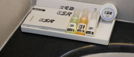 A bathroom shelf with a dental kit, shower gel, shampoo, and body lotion.