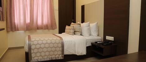 A hotel room with a bed, bedside table, and a wooden headboard.