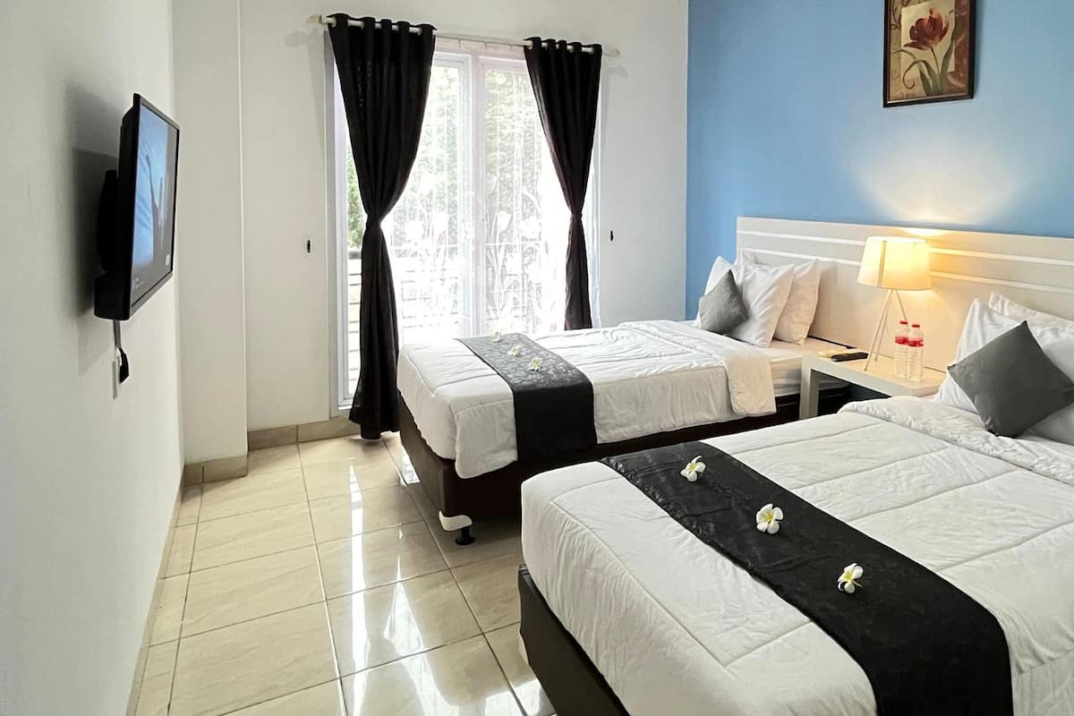 A hotel room with two beds, a TV, a lamp, and a window with curtains.