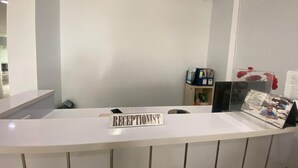 Un comptoir d’accueil avec une pancarte indiquant « RÉCEPTION » et une photo encadrée accrochée au mur.