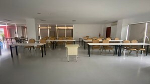 Une salle de conférence dotée de plusieurs tables et chaises, de murs blancs et d’un aménagement épuré et bien organisé.