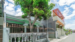 A building with a green and white facade, a tree in front, and a red staircase. - Hotel O Ita Homestay Syariah (Sidoarjo)