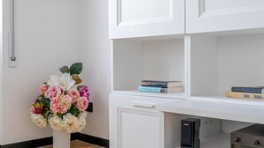 Ein weißes Schränkchen mit Büchern und einer Blumenkomposition.