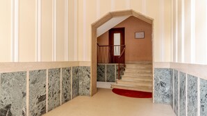 Ein Korridor mit Marmorwänden und einer Holztreppe.