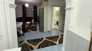 A living room with a sofa, a coffee table, and a TV. There is a hallway leading to a bathroom with a washing machine. - Beautiful 2-bedroom flat sea view Durres (Durres)
