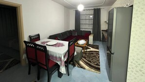 A dining area with a table set for two, a sofa, and a refrigerator. - Beautiful 2-bedroom flat sea view Durres (Durres)