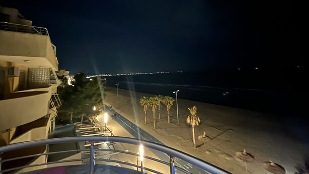 A nighttime view from a balcony overlooking a beach with palm trees and a distant cityscape. - Beautiful 2-bedroom flat sea view Durres (Durres)