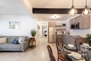 A modern kitchen with a refrigerator, microwave, and dining area with chairs and a table set for a meal. - Prime Location in San Juan, Puerto Rico – Steps from Everything (San Juan)