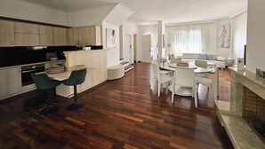Une cuisine moderne avec des meubles en bois, un coin repas avec une table ronde et des chaises, et un salon avec un canapé et une table basse.