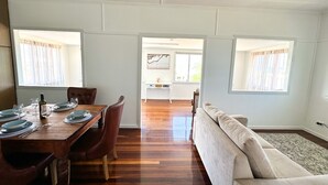 A dining area with a wooden table set for four, a sofa, and a ceiling fan.