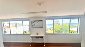 A room with wooden flooring, a white console table with drawers, and a painting on the wall.