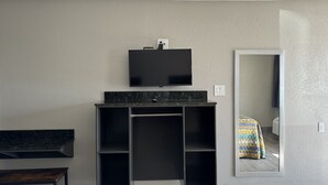 A modern bathroom with a black vanity, a mounted TV, and a large mirror. - Nola Inn & Suites (New Orleans)