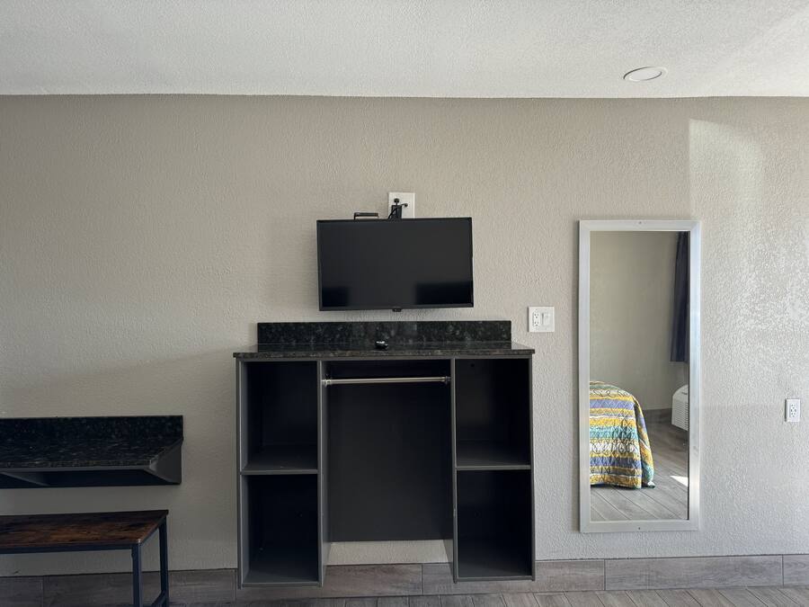 A modern bathroom with a black vanity, a mounted TV, and a large mirror.