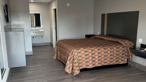 A bedroom with a bed, a small kitchenette, and a bathroom. - Nola Inn & Suites (New Orleans)
