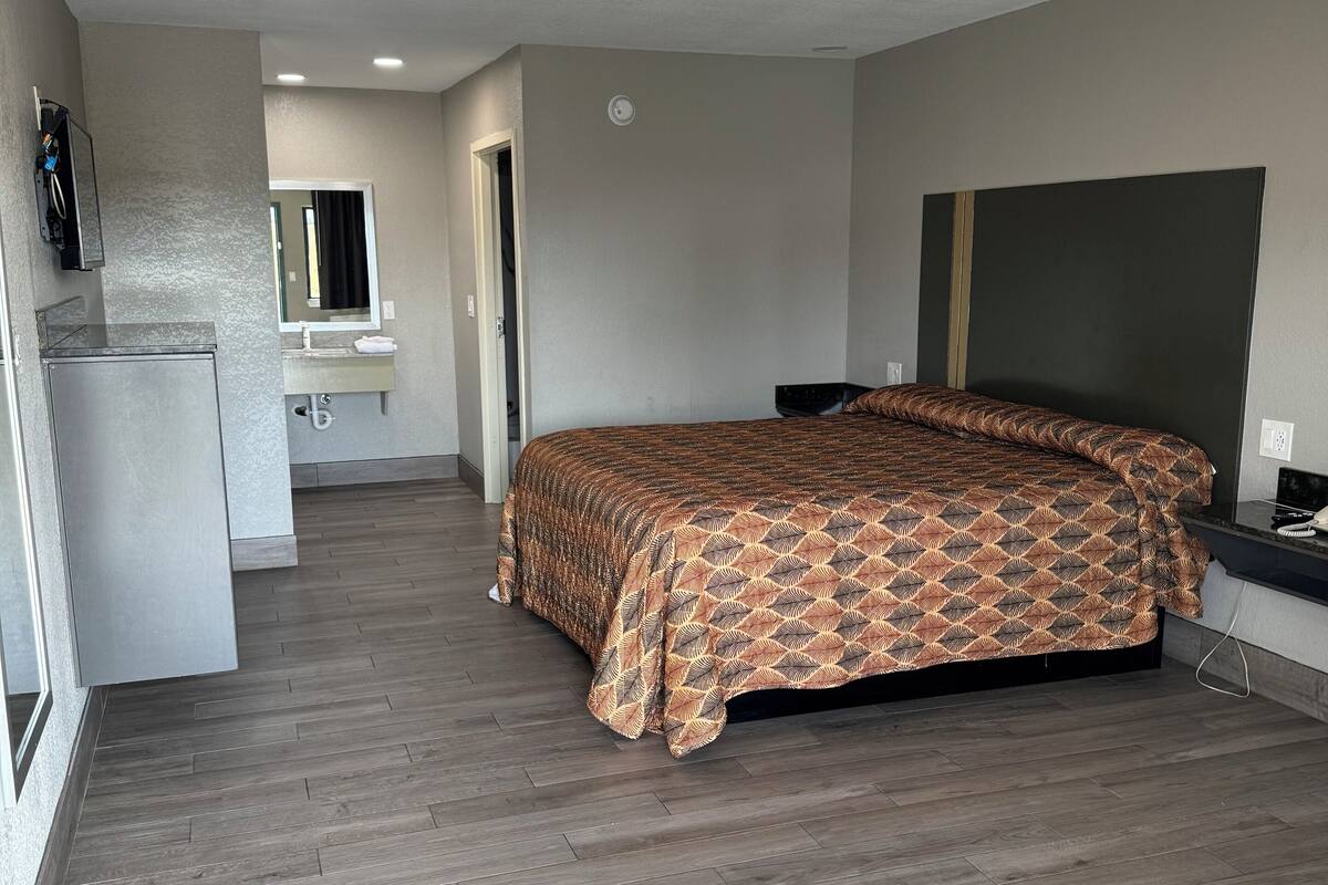 A bedroom with a bed, a small kitchenette, and a bathroom.