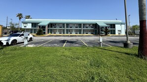 A motel with a light blue exterior, multiple balconies, and a parking lot. - Nola Inn & Suites (New Orleans)