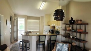 Une cuisine moderne dotée d’un îlot central, de tabourets de bar et d’un luminaire suspendu.