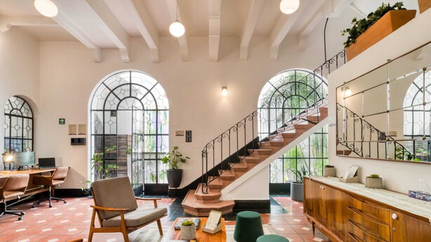 Un hall d’entrée spacieux avec un escalier, un coin salon et de grandes fenêtres.