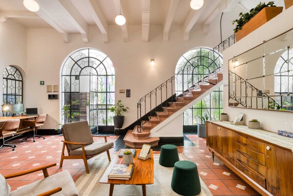 A spacious lobby with a staircase, seating area, and large windows.